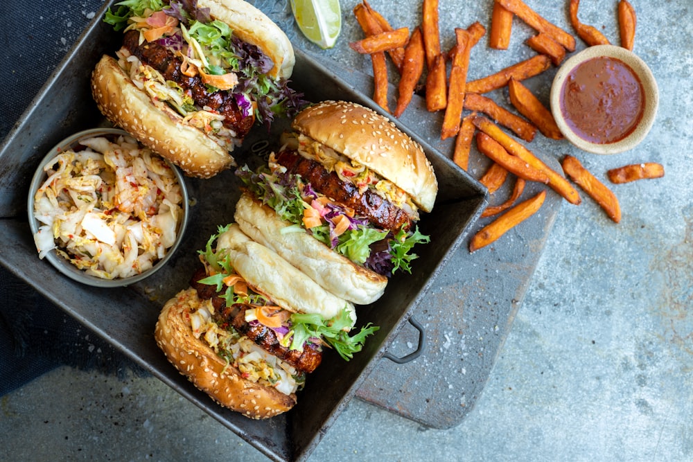 a tray filled with sandwiches and fries next to a bowl of coleslaw