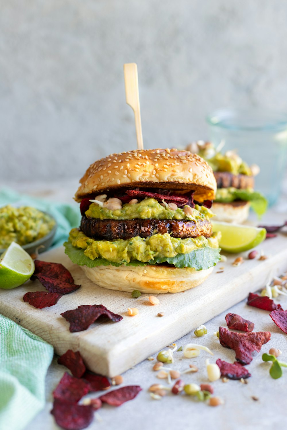 a burger with guacamole and other toppings on a cutting board