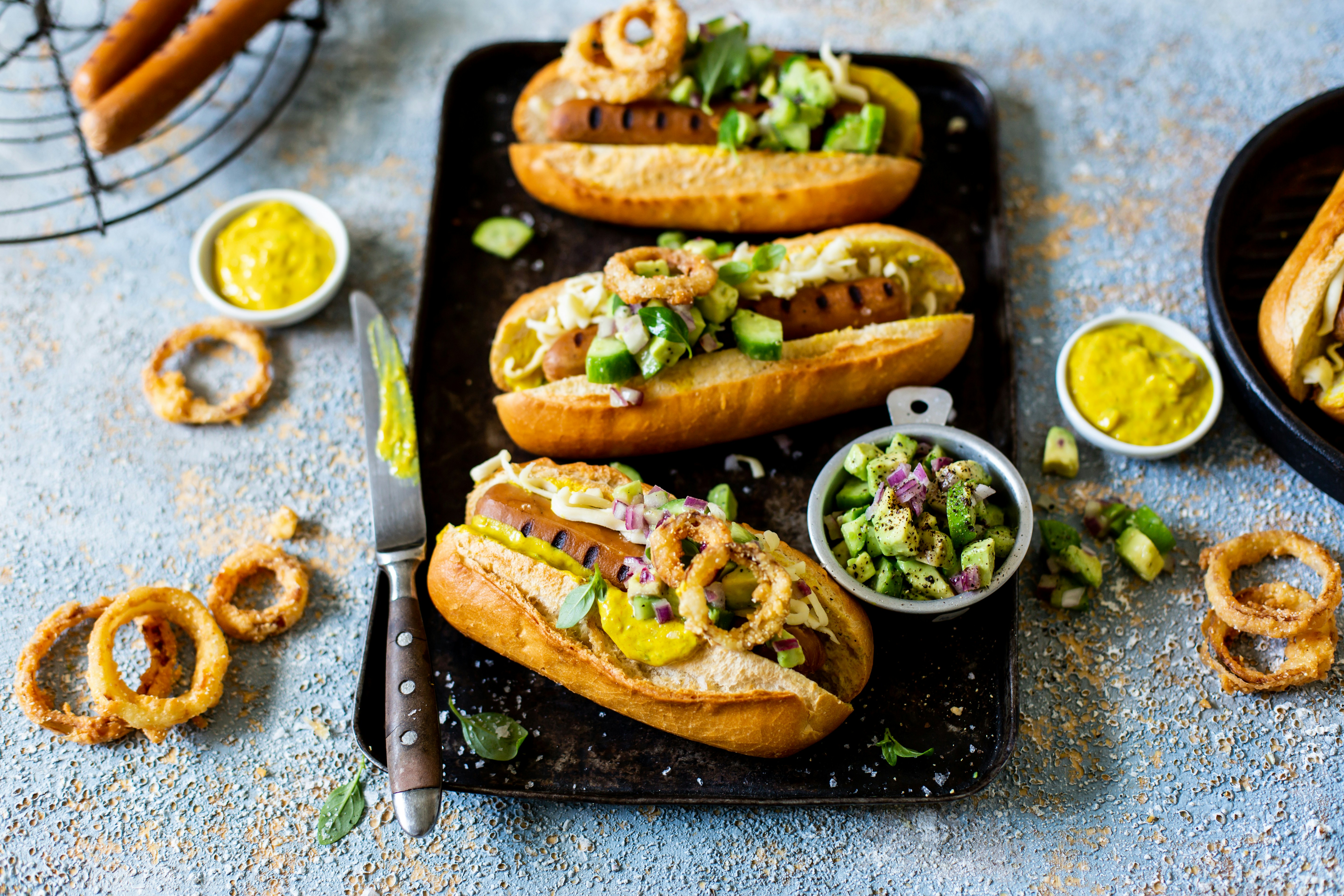 three hot dogs on a tray with onion rings