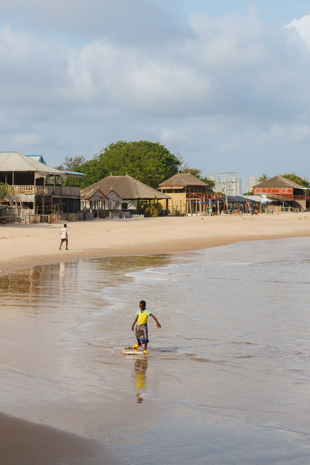 a young boy standing on top of a surfboard in the ocean