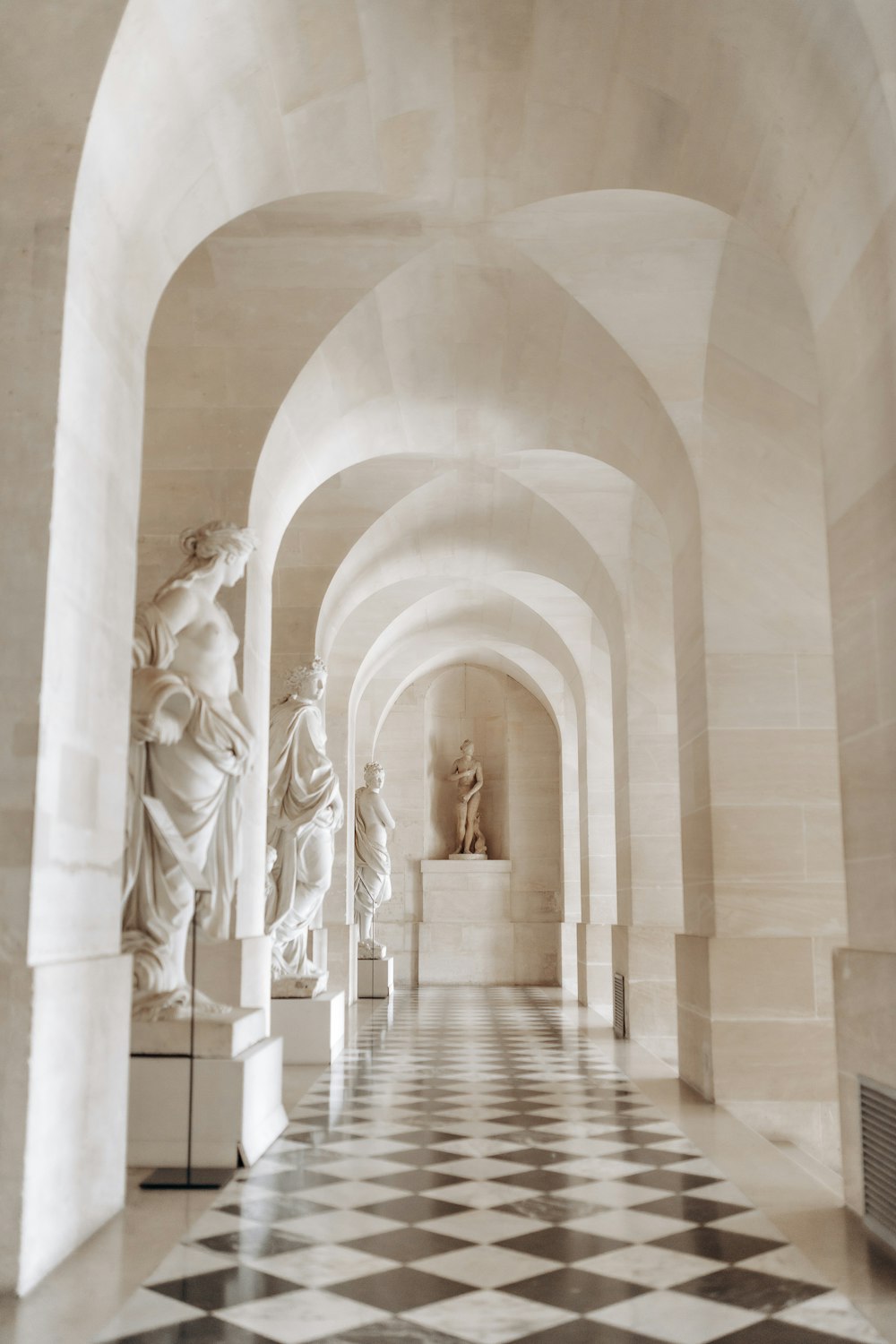 a black and white photo of a hallway with statues