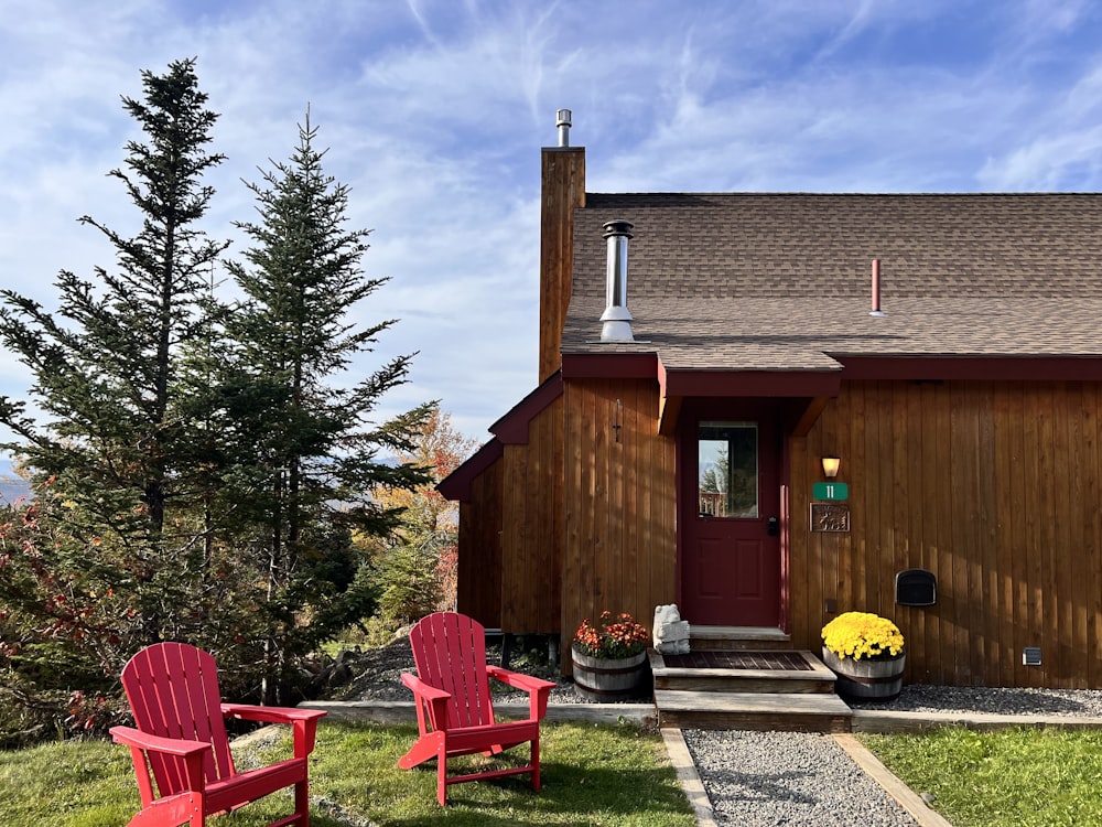 two red chairs sitting in front of a house