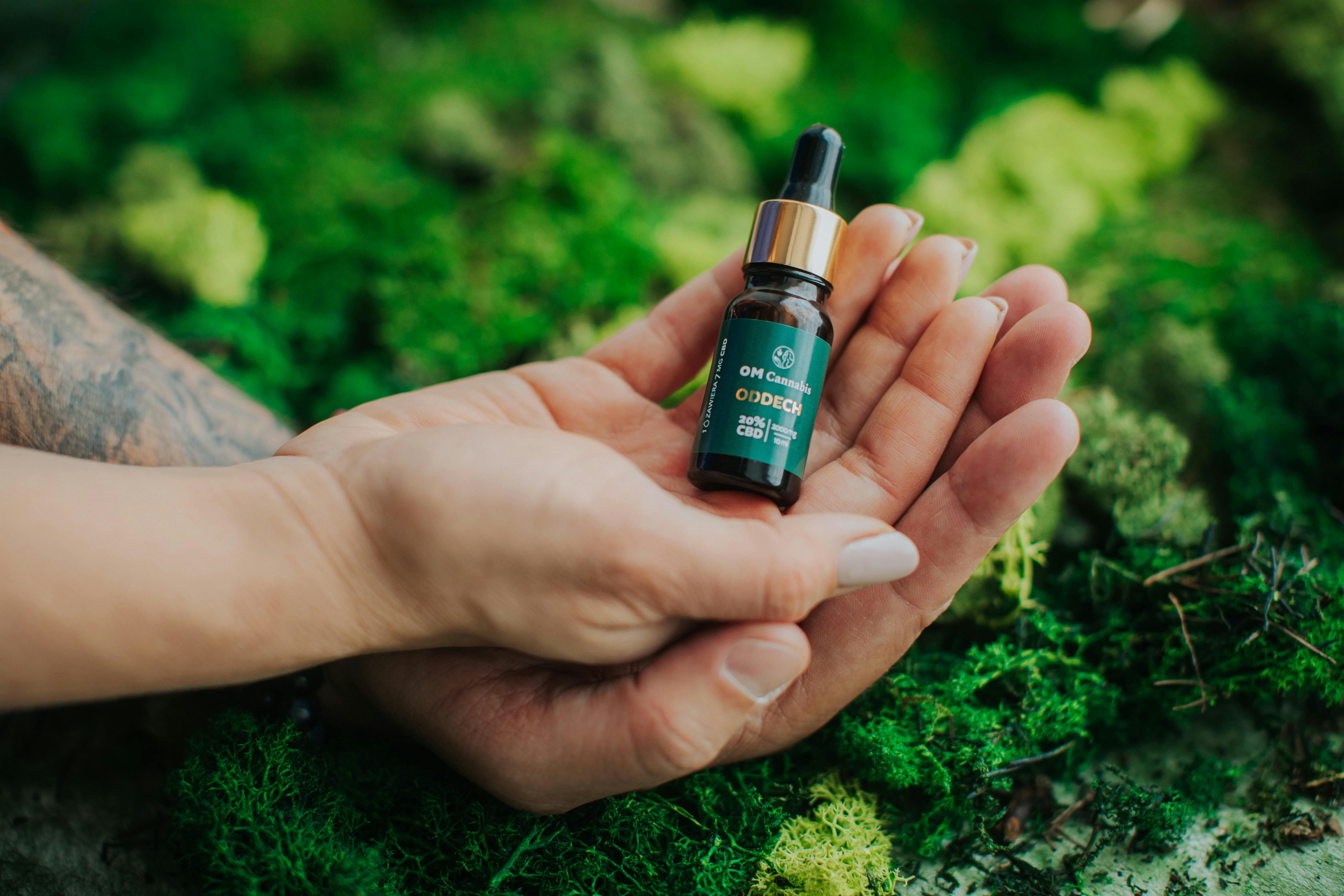 a person holding a small bottle of essential oil