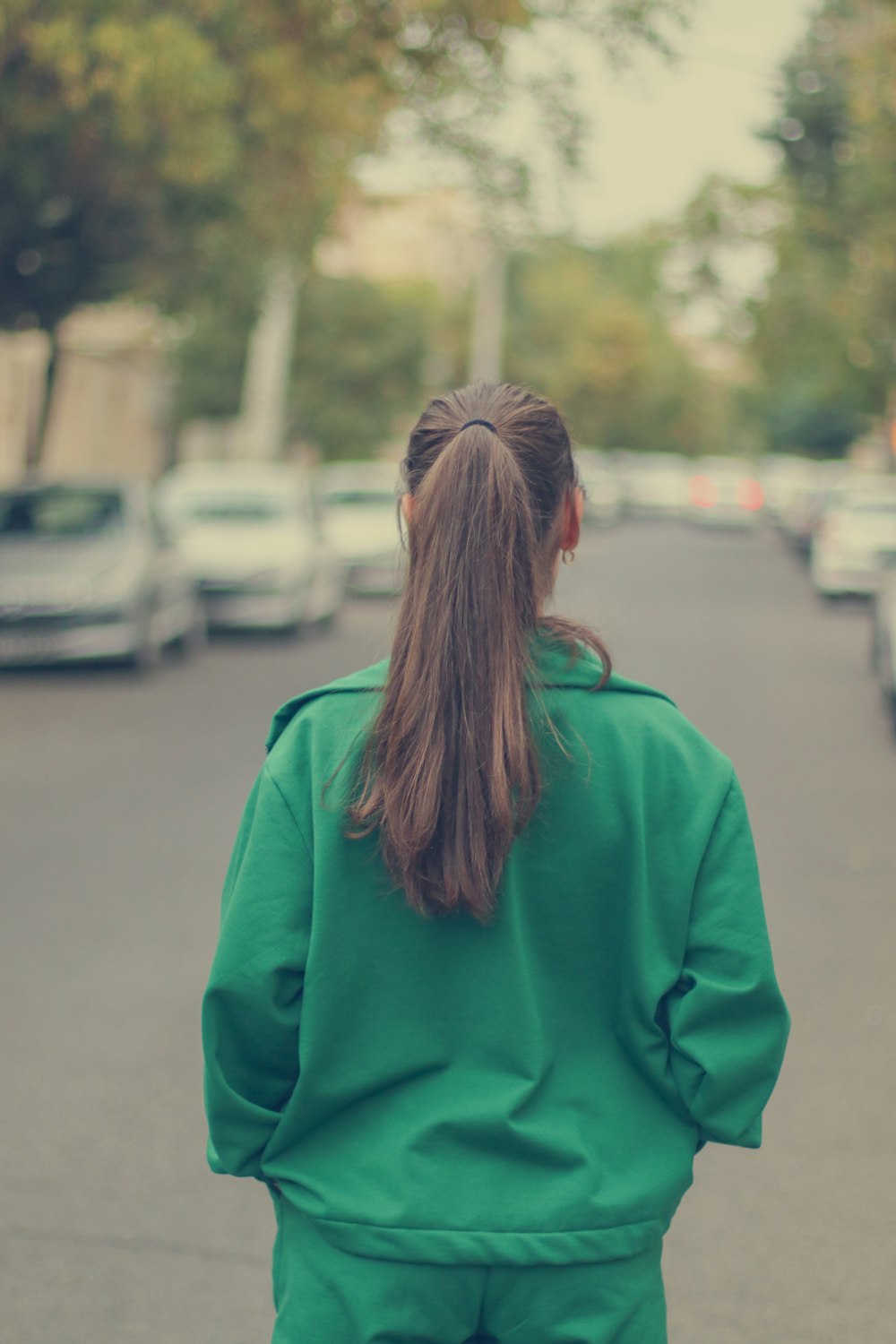 a woman walking down a street in a green jacket