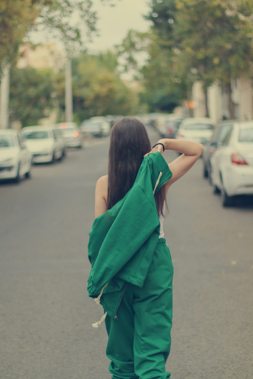 a woman walking down the street in a green outfit