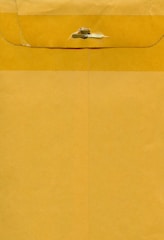 A large brown envelope with a metal clasp closure at the top. The envelope appears to be made of kraft paper with visible creases and texture.