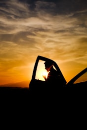 A friendly driver opening car door for a passenger at sunset.