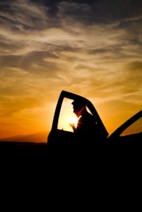 A friendly taxi driver opening the car door for a passenger at sunset.