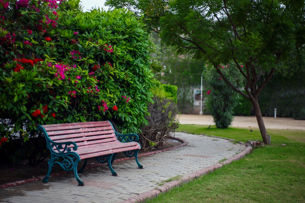 a park bench sitting next to a lush green bush