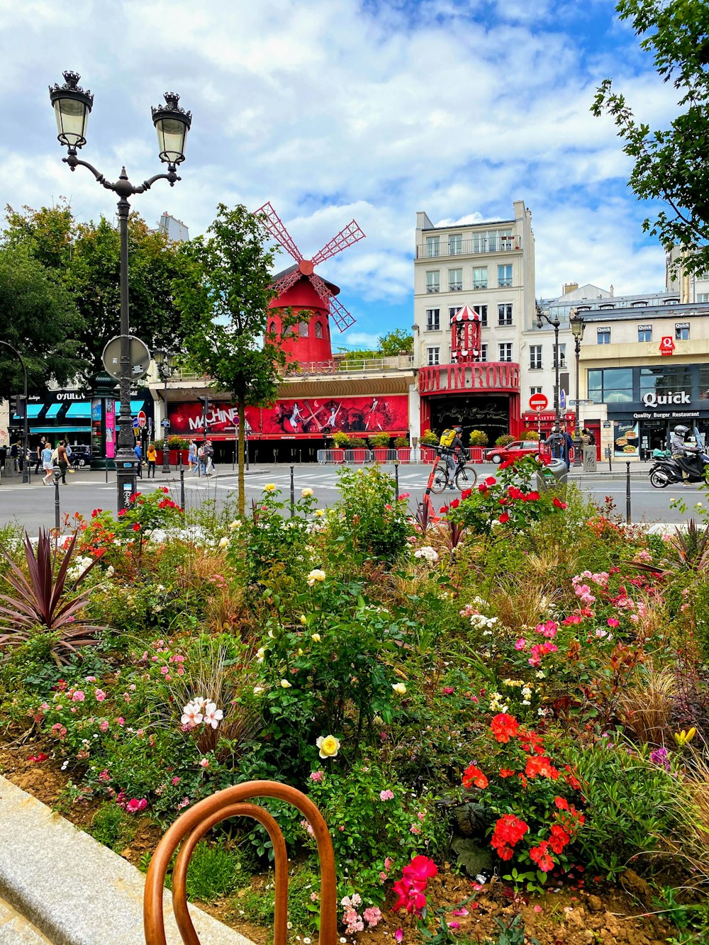 a flower garden with a windmill in the background