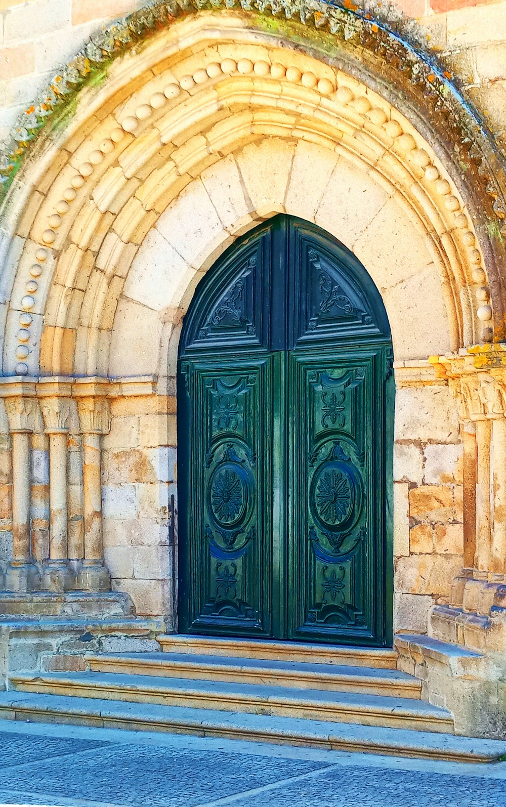 a large green door sitting in front of a stone building