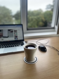 Modern office workspace with a laptop and coffee cup on the desk.