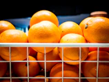 A colorful display of fresh oranges and mosambi stacked in baskets.