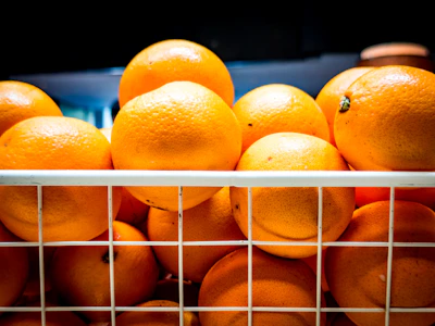 A colorful display of fresh oranges and mosambi stacked in baskets.