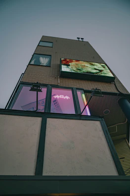 Street-level view of a commercial building covered in transparent LED displays capturing passerby attention.