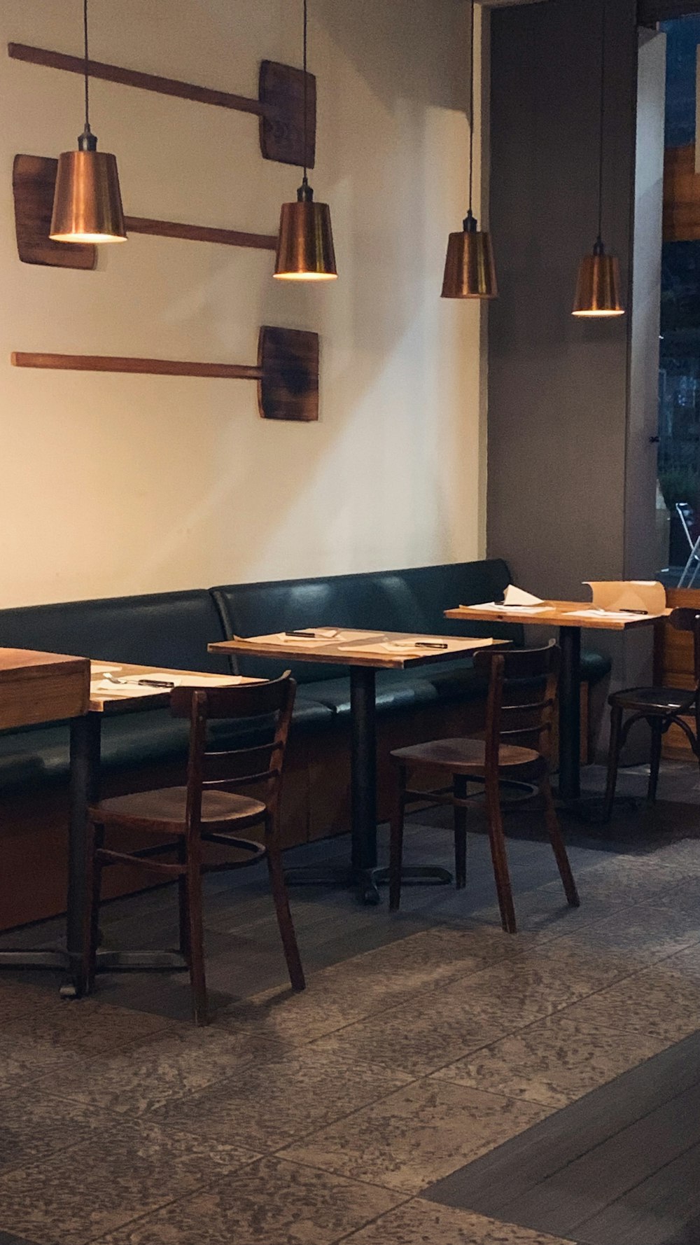 a restaurant with wooden tables and green booths