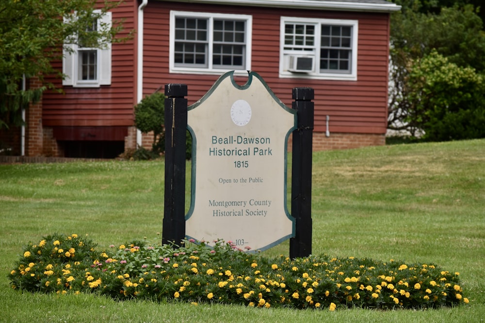 a sign for a historical park in front of a red house