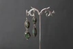 A pair of elegant drop earrings displayed on a velvet cushion