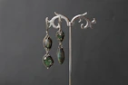 A pair of elegant drop earrings displayed on a velvet cushion