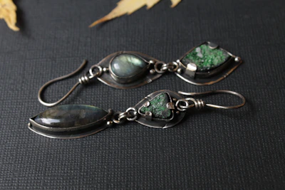 Pair of handcrafted silver earrings with shimmering natural gemstones catching the light.