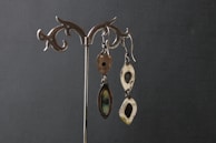 Earrings hanging from a decorative stand against a soft backdrop.