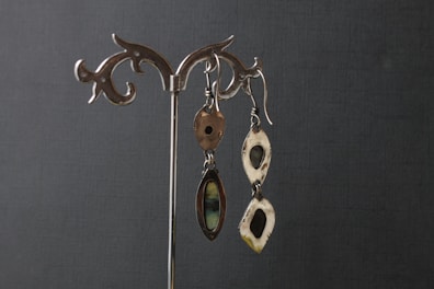 Shiny silver earrings displayed on a rustic wooden surface
