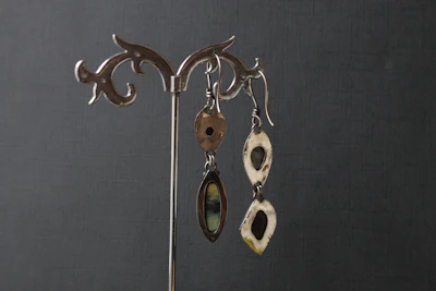 Artistic shot of delicate earrings hanging from a minimalist geometric stand with soft shadows.