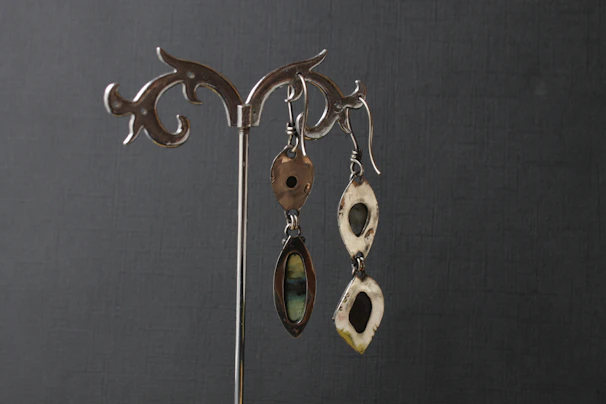 A pair of shimmering silver earrings displayed on a rustic wooden surface.
