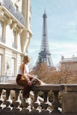 a woman sitting on a ledge in front of the eiffel tower