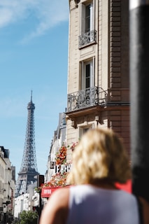 a woman is walking down the street in front of the eiffel tower