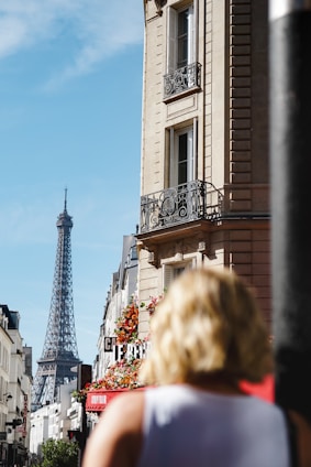 a woman is walking down the street in front of the eiffel tower