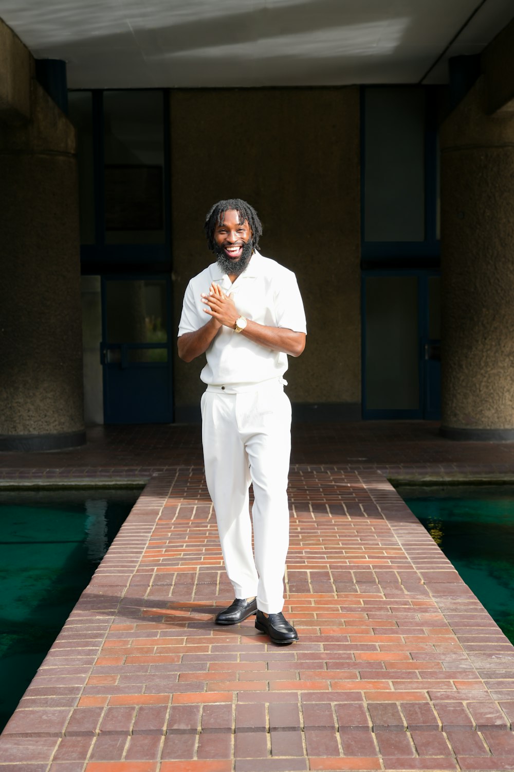 a man standing on a brick walkway next to a pool