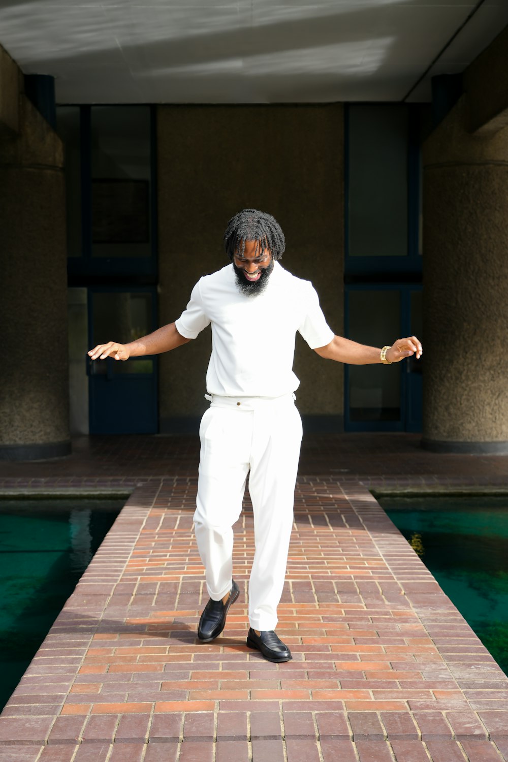 a man standing on a brick walkway next to a pool