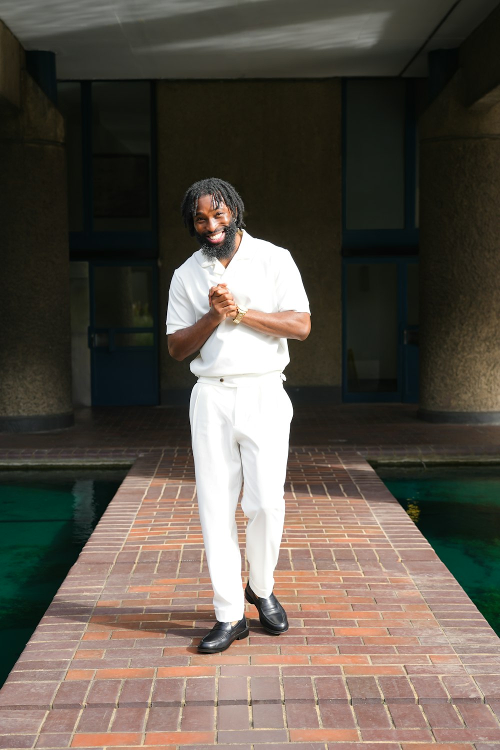 a man standing on a brick walkway next to a pool