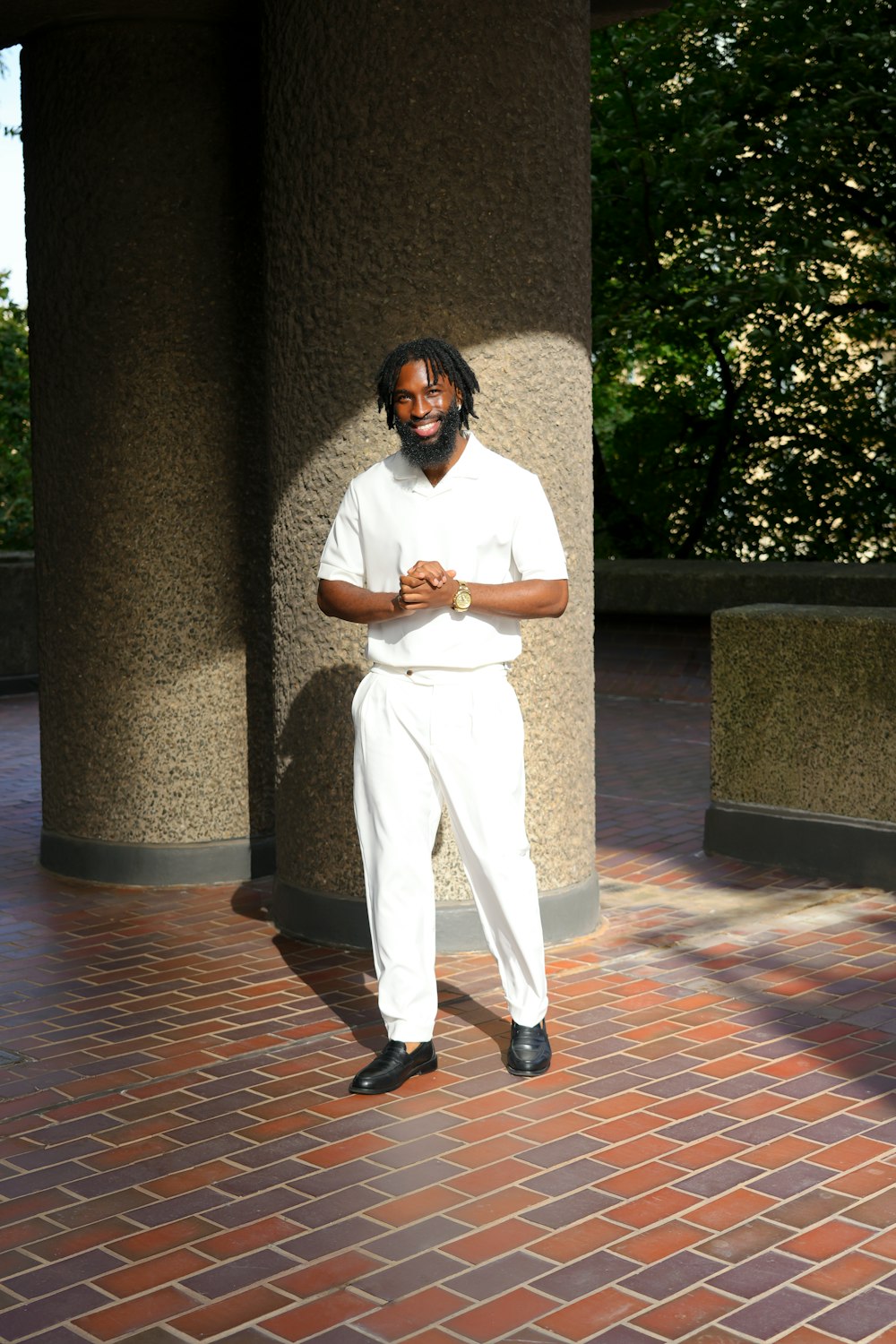 a man in a white outfit standing next to a pillar