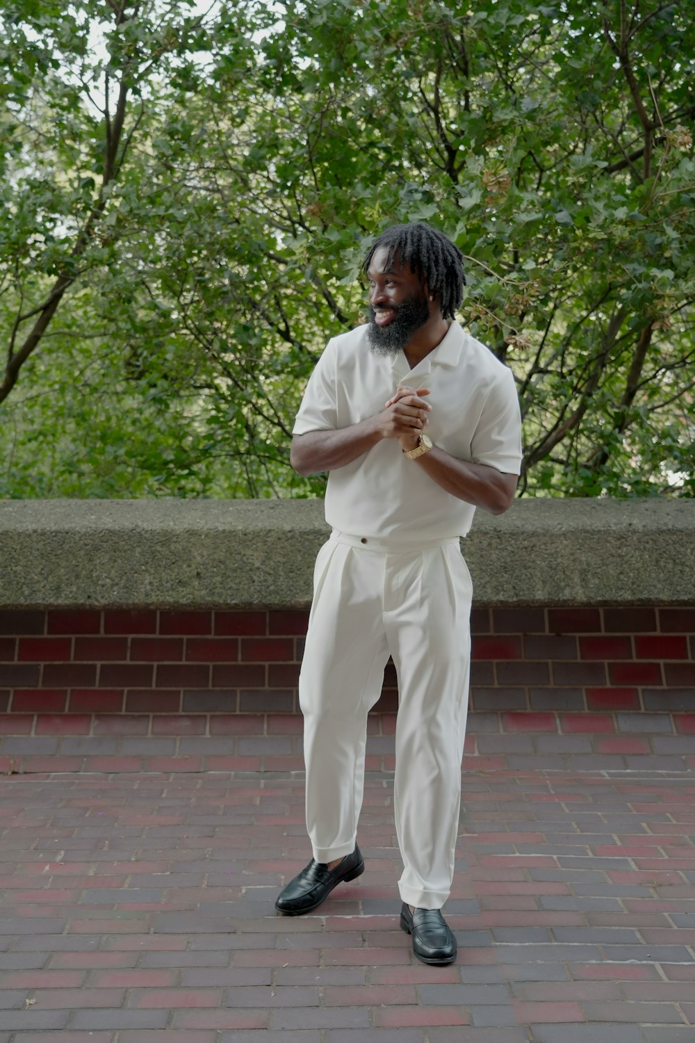 a man in a white suit standing on a brick walkway