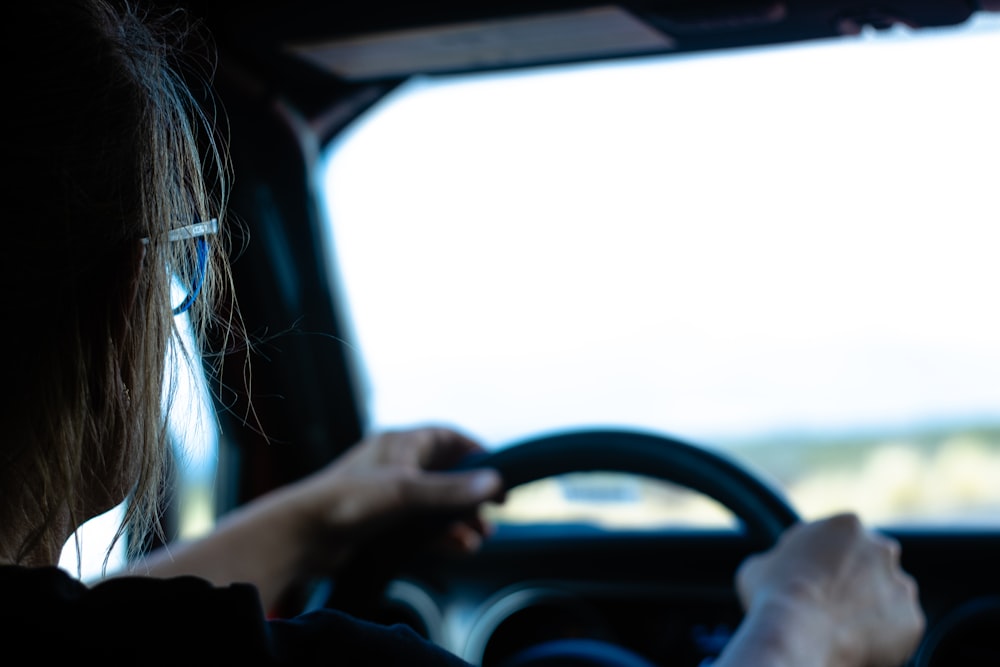 a woman driving a car with a steering wheel