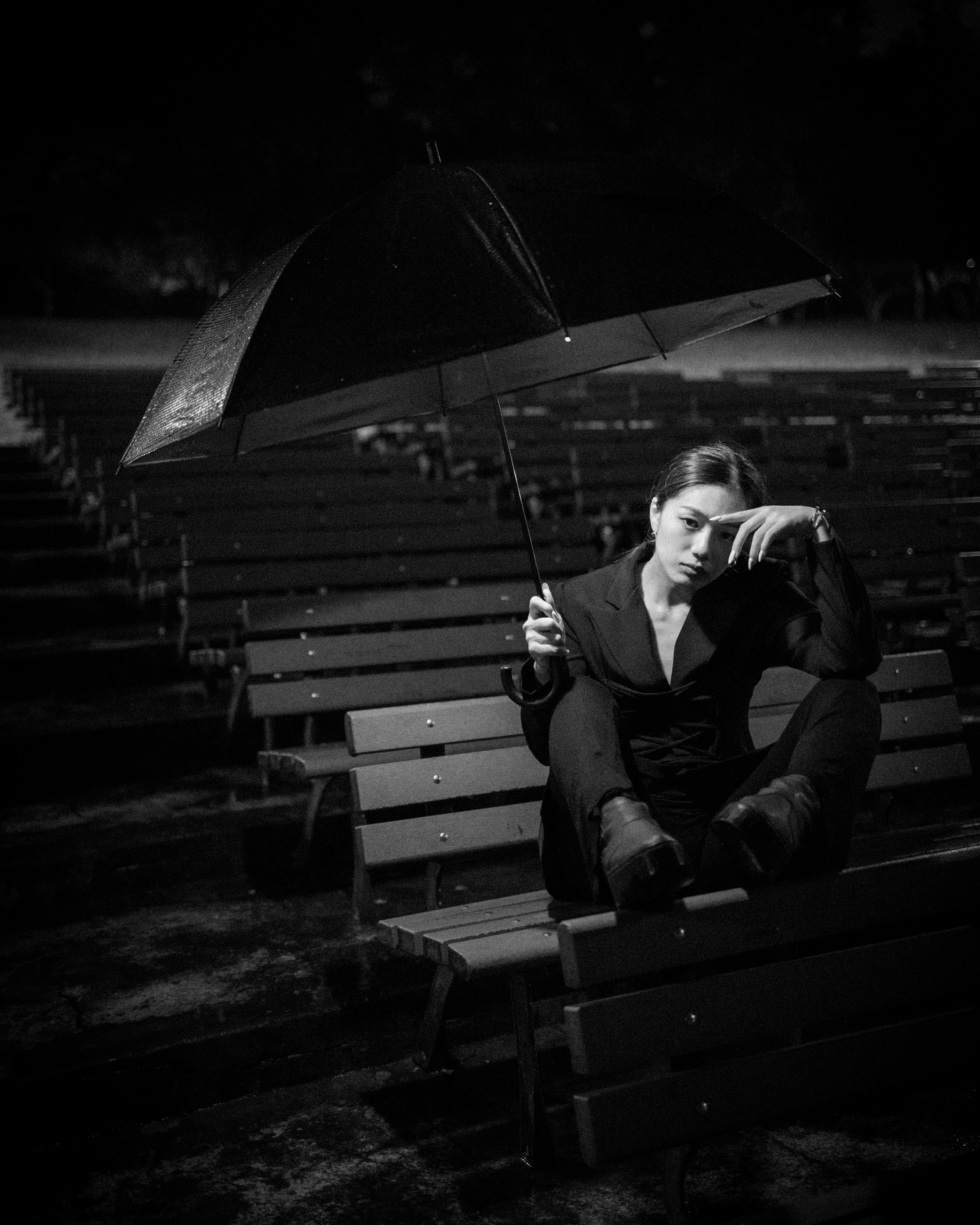 a woman sitting on a bench holding an umbrella