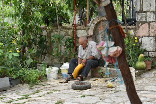 An elderly man wearing a comfortable fall detection smartwatch while gardening.
