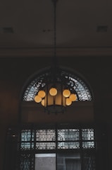 Artistic wrought iron chandelier with intricate scrollwork hanging in a cozy room.