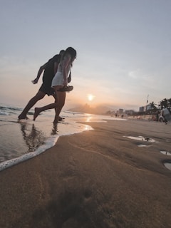Couple enjoying a sunset walk along the Riviera Maya coastline with palm trees and soft sand.