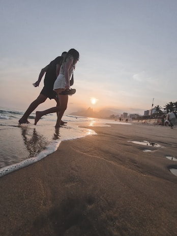 Couple enjoying a sunset walk along the Riviera Maya coastline with palm trees and soft sand.