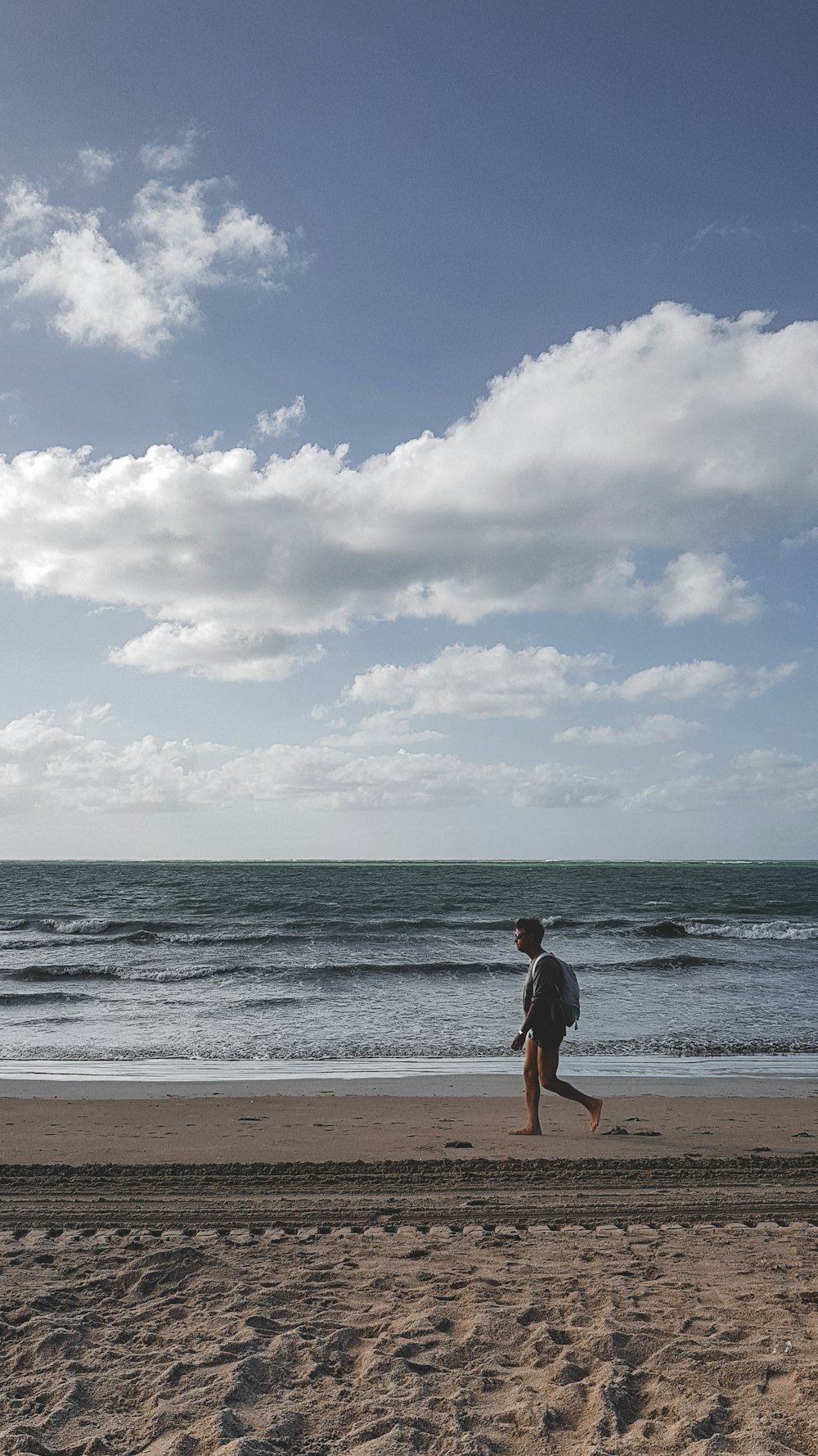 um homem correndo em uma praia perto do oceano