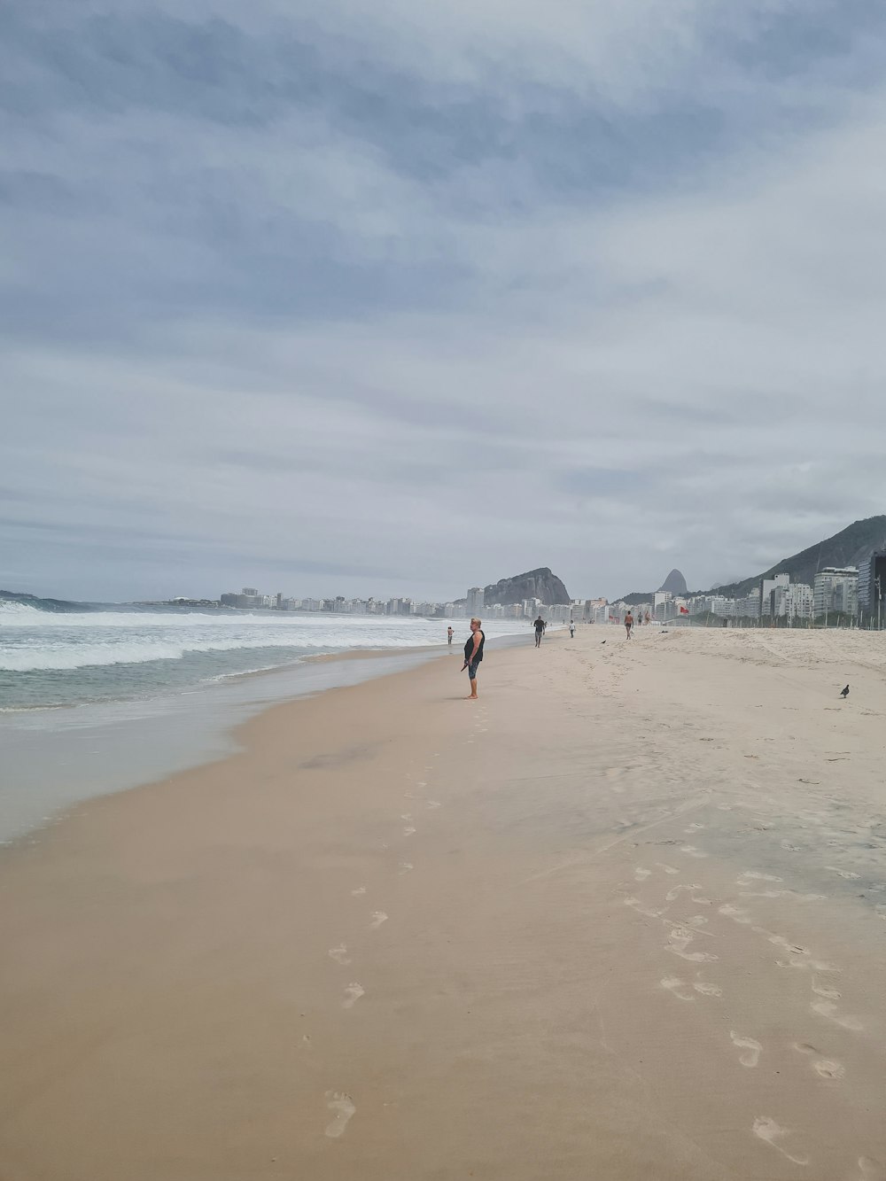 a group of people walking along a beach next to the ocean