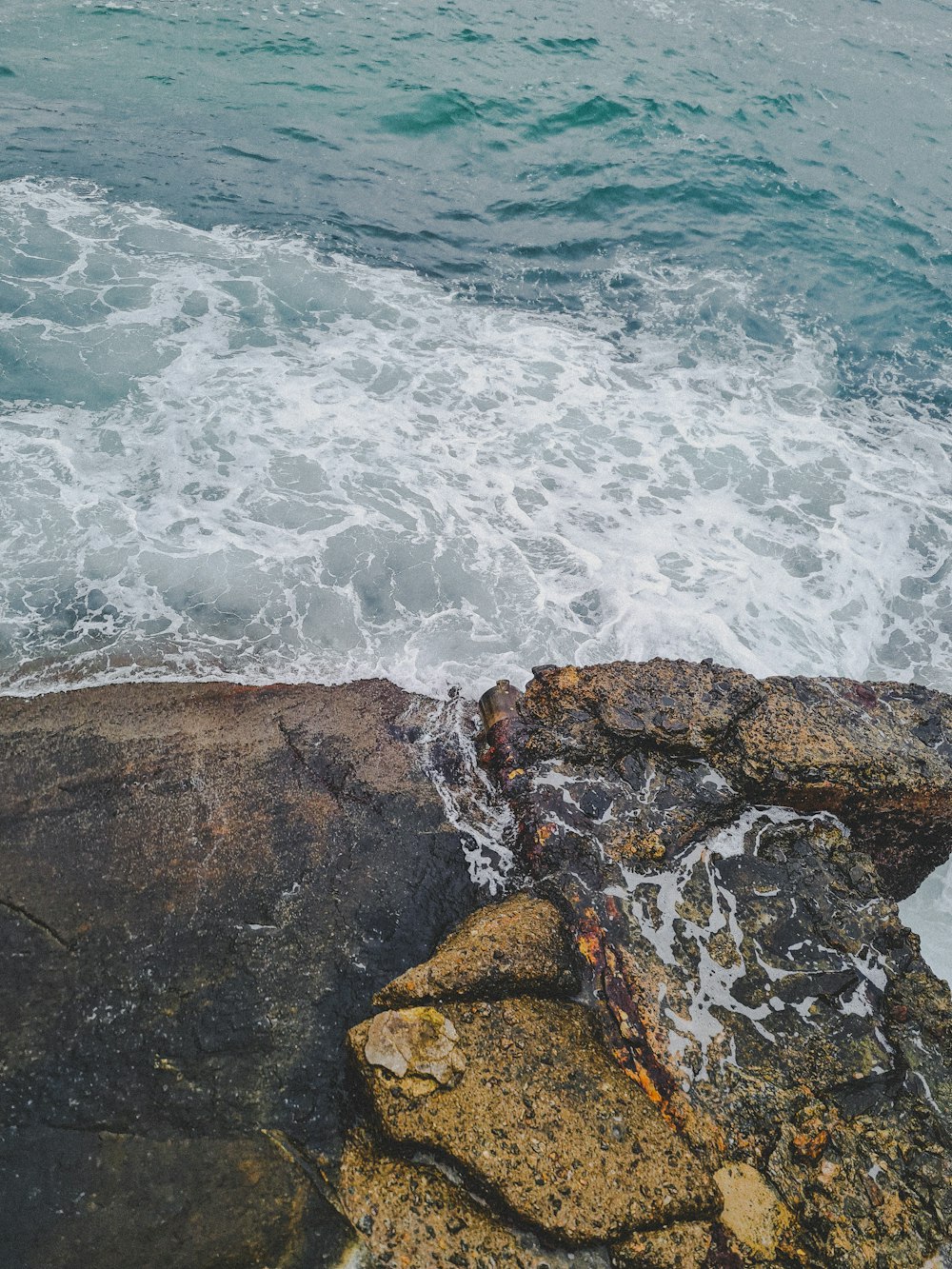 a person sitting on a rock next to the ocean