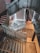 A modern indoor staircase with glass railings and a sleek, architectural design. The stairs spiral down, creating geometric patterns. Fire extinguishers are visible at one of the landings, and there are bright accent lights illuminating the space.