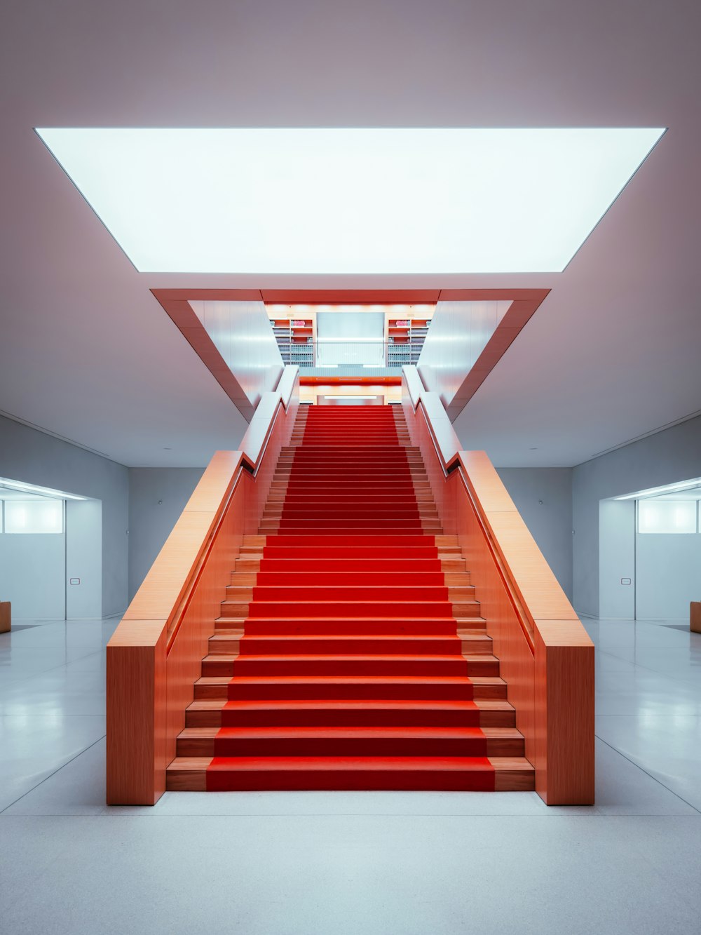 Una scala con moquette rossa che porta a un muro bianco