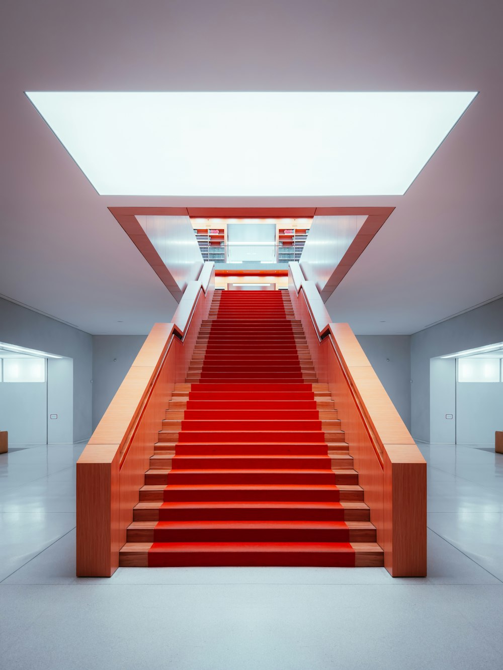 a red carpeted staircase leading up to a white wall