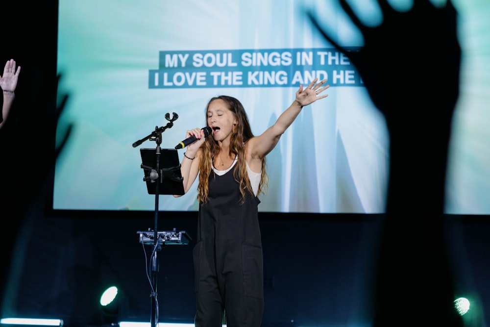 a woman standing in front of a microphone on a stage