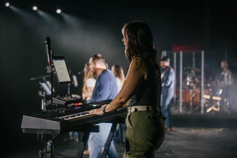 a woman standing at a keyboard in front of a crowd of people